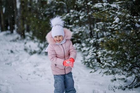 little girl plays snowballs outdoors in winter in forestの写真素材
