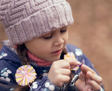 little cute girl in spring forest with flowersの写真素材