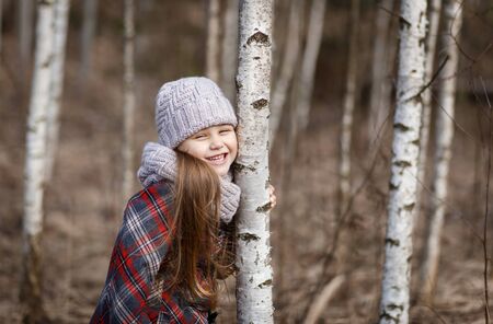 little cute girl hugs a birchの写真素材