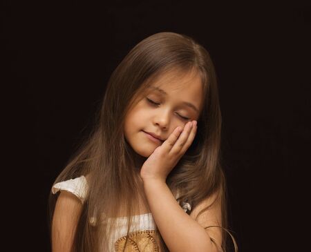 portrait of a little girl with long hair against a dark backgroundの写真素材