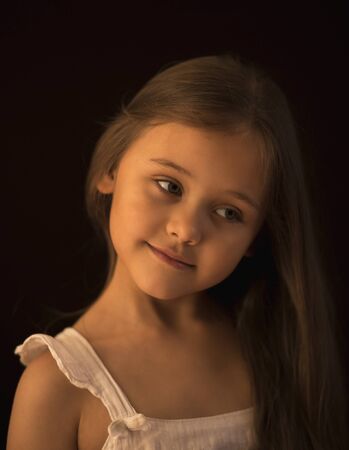 portrait of a little girl with long hair against a dark background