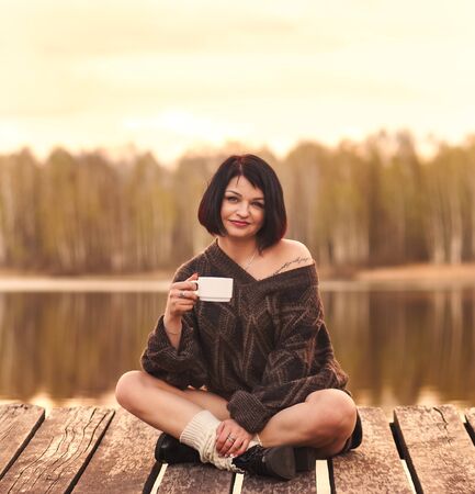 young cute girl drinks coffee outdoors emotionsの写真素材