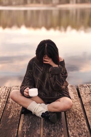 young cute girl drinks coffee outdoors emotionsの写真素材
