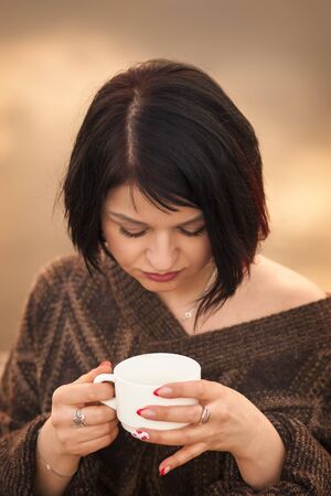 young cute girl drinks coffee outdoors emotionsの写真素材