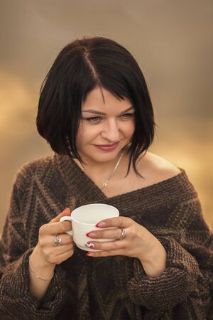 young cute girl drinks coffee outdoors emotionsの写真素材