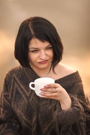 young cute girl drinks coffee outdoors emotionsの写真素材