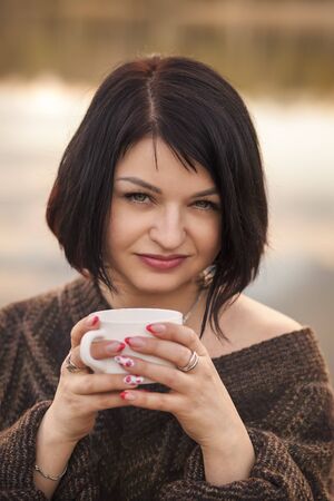 young cute girl drinks coffee outdoors emotionsの写真素材