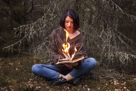 the book burns in the hands of a woman in nature