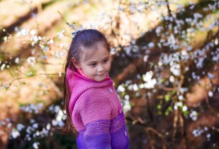 portrait of a little cute girl in a flowered gardenの写真素材