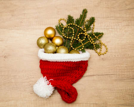 Christmas composition of balls and fir branches in a Santa Claus hat on a white wooden backgroundの写真素材