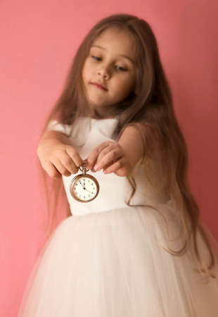 little girl joyful opens a gift box on a pink backgroundの写真素材