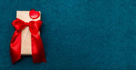 Gift box with tape and heart on a bright blu background.の写真素材