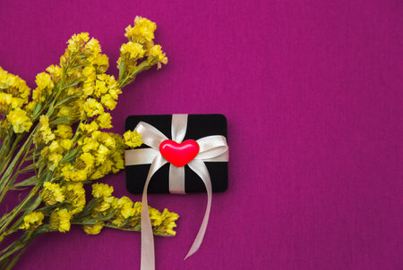 Gift box and yellow flowers on a bright pink background. Copy spaceの写真素材