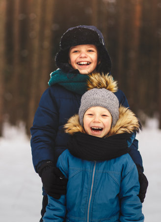 Two brothers laugh in nature in winter forestの写真素材