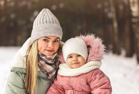 Portrait of a young mother and little daughter in the winter in the woods. A look at the cameraの写真素材