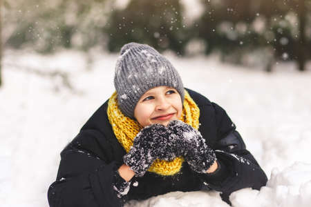 A happy teenage boy lies in the snow. Trend colors 2021の写真素材