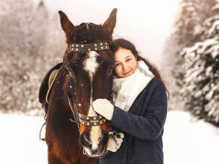 Young pretty girl hugs horse in winter in natureの写真素材