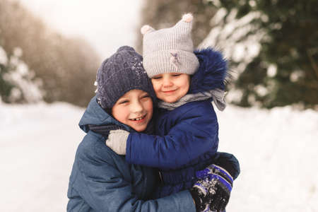 Happy children cuddle in winter in the woods. Brother and sister togetherの写真素材