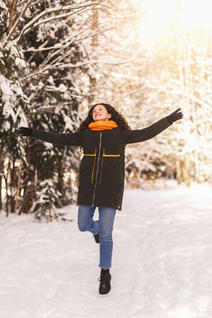 A young girl happily runs through the snow in the winter forest. Emotions