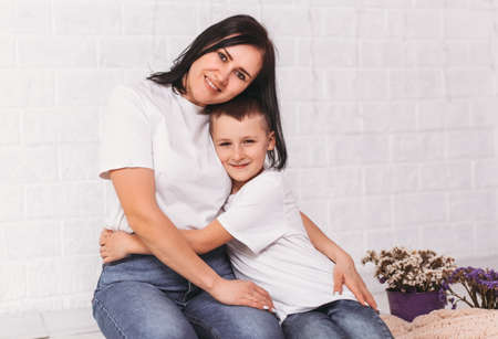 Young mother hugs her son on a white background
