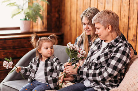 three generations of women, mother, grandmother and granddaughter with flowersの写真素材