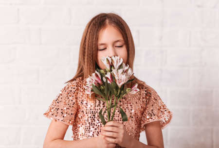 Beautiful teenage girl with a bouquet of spring flowers on a white backgroundの写真素材