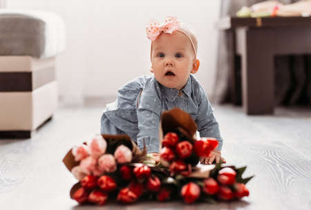 Little girl infant with a large bouquet of tulip flowers.の写真素材