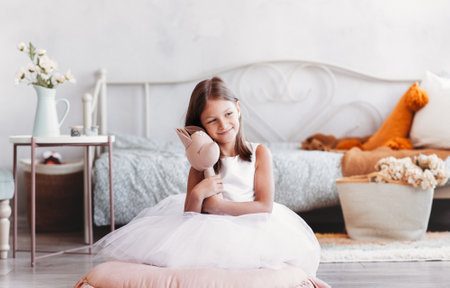 A beautiful little girl plays with a toy on the floor in a light room. Happy smiling babyの写真素材