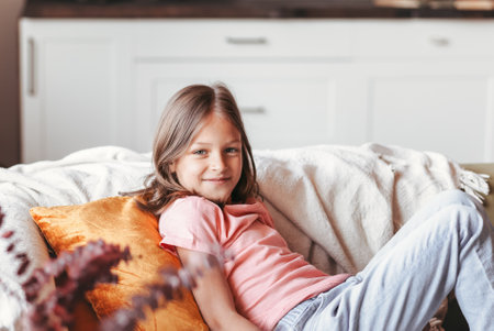 Little cute girl lies on the couch in t-shirt and jeans and smilesの写真素材