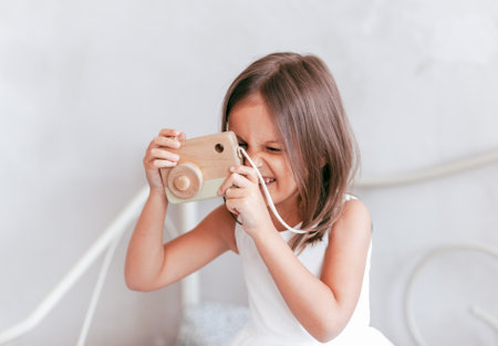 A little girl plays with a toy camera. Takes a picture of a childの写真素材