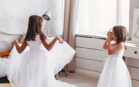 Two little girls girlfriends play fun in a light room. Friendly sisters togetherの写真素材