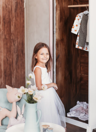 Cute beautiful girl stands by the open closet and smiles in the light roomの写真素材