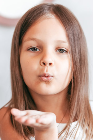 A little girl sends an air kiss. Close-up portraitの写真素材