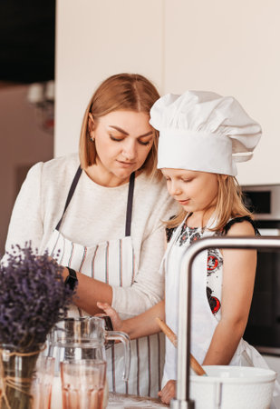 A young mother teaches her daughter to cook in the kitchen. Time with familyの写真素材