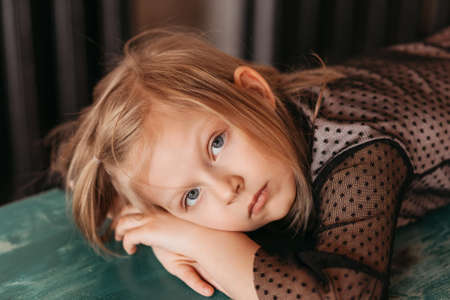 Portrait of a beautiful sad girl. A girl lies on the floor in the living roomの写真素材