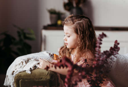 A little girl misses on the couch in the living room. Children's emotions