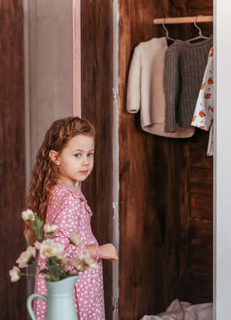 Little girl opens a closet with clothesの写真素材