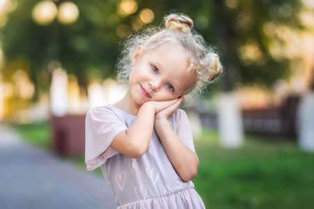Pretty little girl posing for camera in the summer in the parkの写真素材