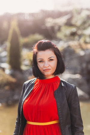 Portrait of a beautiful young woman in nature in a red dress. A look at the cameraの写真素材