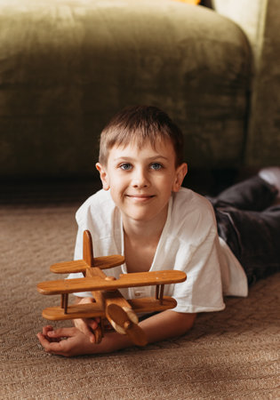 A boy plays with a wooden toy plane in the living room. Longing for travelの写真素材