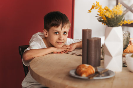 A school-age boy sits at the kitchen table. Waiting for lunch