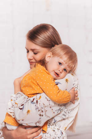 Young beautiful mom gently hugs her little daughter. Verticalの写真素材