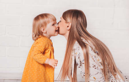 Young beautiful mother wants to kiss her little daughter. Mom and Her Child Having Fun togetherの写真素材