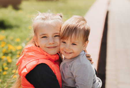 Older sister hugs her little brother in summer in the parkの写真素材