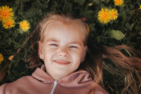 Cute school-age girl lies on the grass in the park in the summer