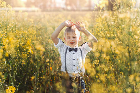 little cute boy in an oilseed rape field. Rural landscape. Vertical