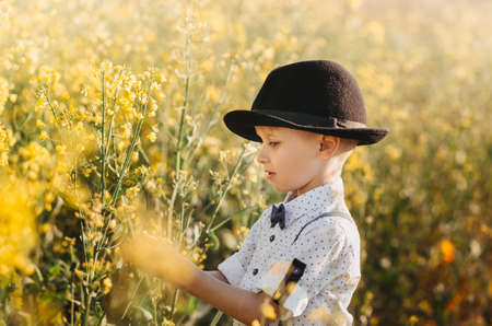 little cute boy in an oilseed rape field. Rural landscape. Verticalの写真素材