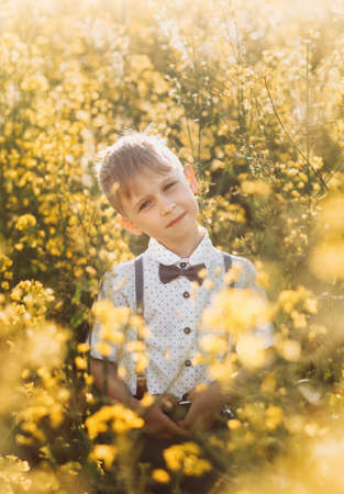 little cute boy in an oilseed rape field. Rural landscape. Verticalの写真素材