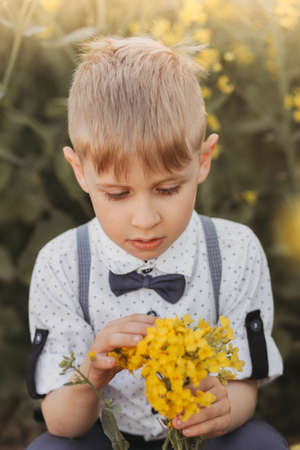 little cute boy in an oilseed rape field. Rural landscape. Verticalの写真素材
