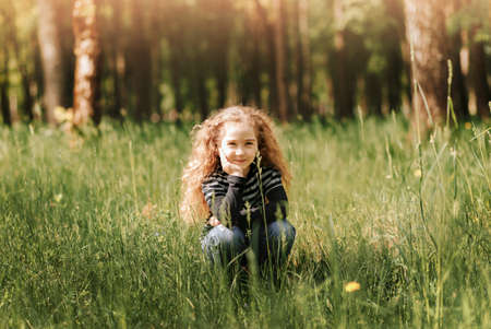 Little girl with curly hair in the park with a bouquet of wildflowersの写真素材
